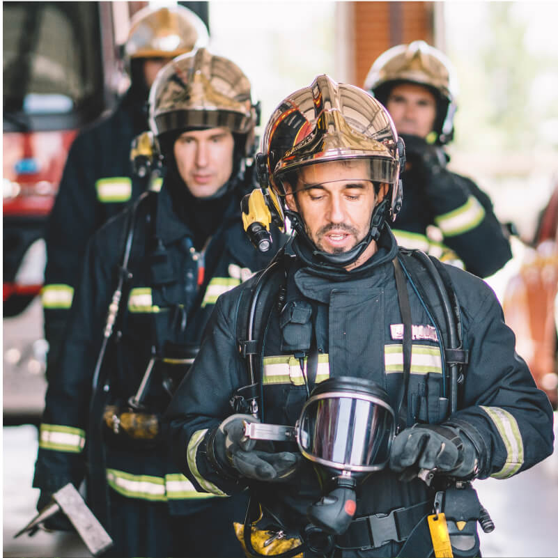 A group of firefighters poses proudly in front of a fire truck, showcasing their dedication and teamwork in emergency response.