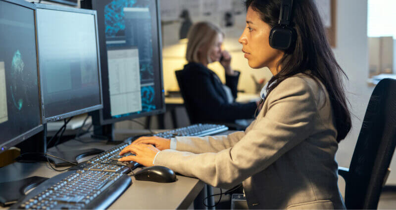 A woman dispatcher wearing headphones, focused on her work at a computer, immersed in her tasks.