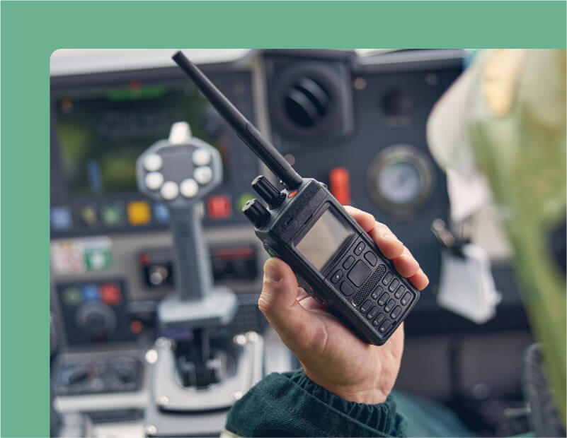 A person operating a radio while seated in the cockpit of an aircraft, focused on communication and navigation.